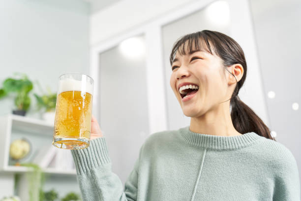 自宅でジョッキからビールを飲む女性 - アルコール 顔つき ストックフォトと画像