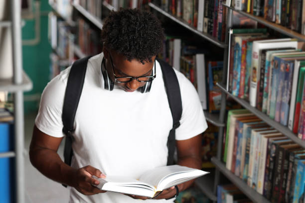 istock African university student with backpack reads an interesting book in library 2149080019