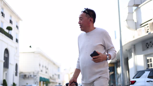 A senior Asian man traveler navigates through the streets while using her smartphone while exploring Georgetown, Penang