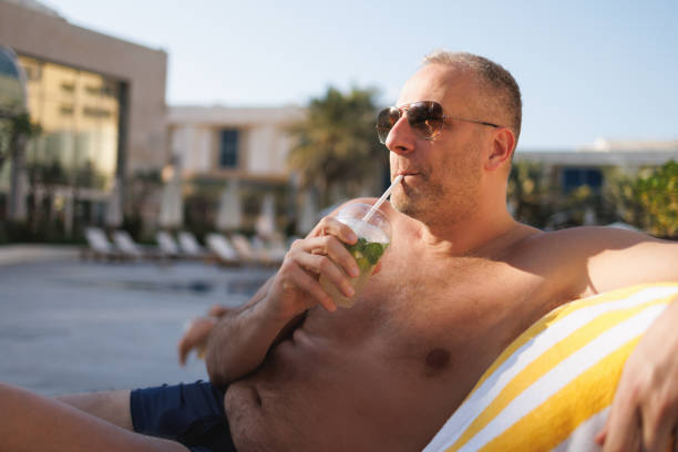 A can of drink by the pool. A girl with a drink is relaxing by the hotel pool.