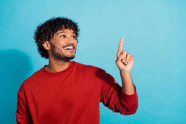 istock Photo of indian model guy in red pullover directing finger empty space interested touching new technology isolated on cyan color background 2149080957