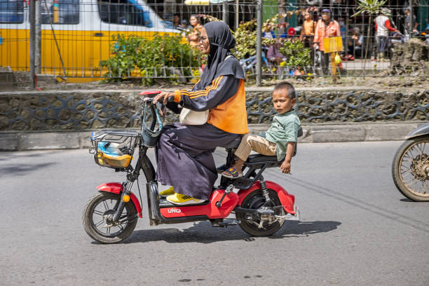 Berastagi, North Sumatra, Indonesia - January 27th 2024:  Mother and son on a electric motorcycle