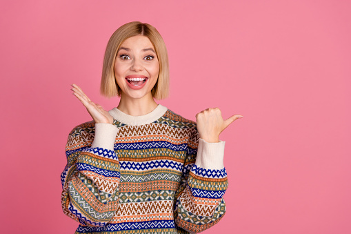 Portrait of ecstatic woman with bob hair dressed print jumper directing at unbelievable sale empty space isolated on pink color background.