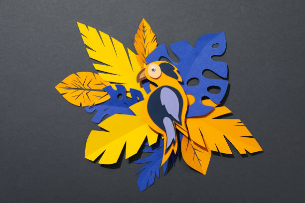 istock Paper yellow, blue tropical leaves on a dark, gray background. With a parrot. 2149085819