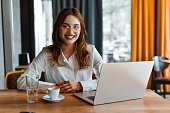 Smiling Beautiful Female Radiating With Confidence While Working Remotely From Coffee Bar