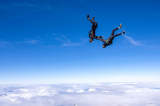 Freefall jumpers hold hands upside-down mid-air