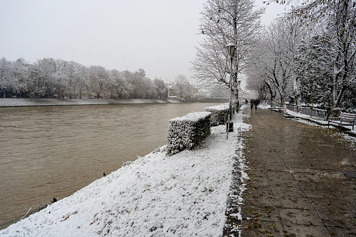 Snowfall in the city. dirty river in winter