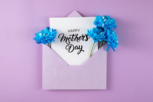 Flowers with purple envelope and greeting card on purple background