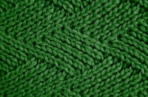 Knitted green wool scarf with a diamond pattern. Abstract background. Close-up. Selective focus.
