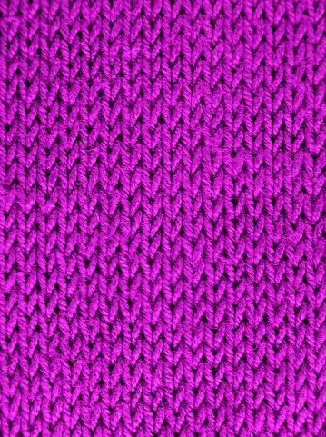 Texture of knitted wool fabric with of a pink color. Close-up. Selective focus.