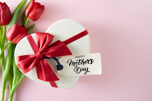 Mother’s Day concept with red and white tulips and heart shaped gift box on pink background