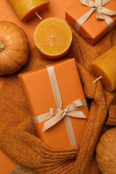 istock Candles, pumpkin and boxes on sweater on orange background, top view 2149091689
