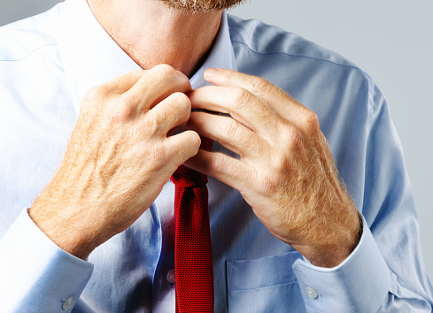 Man getting dressed or worried about his appearance adjusts his tie.