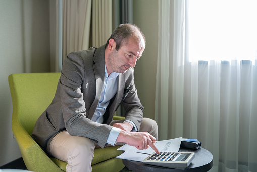 Businessman Using Calculator To Maximize Sales Profit At Hotel Room