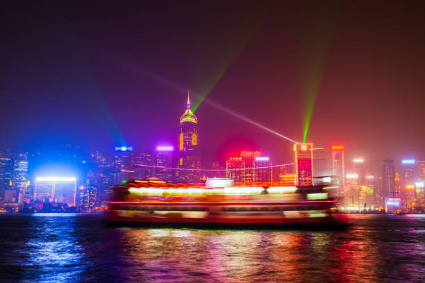 A striking red traditional junk boat sail illuminated by the vibrant Hong Kong skyline at night, showcasing cultural contrast and urban beauty.