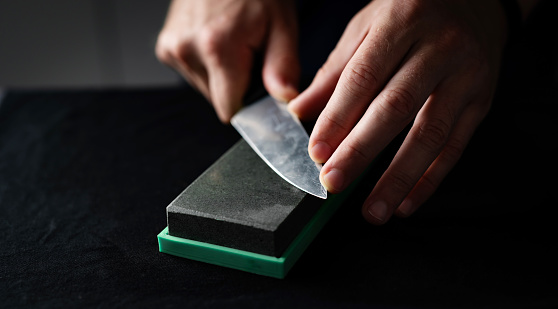 Close Up Of A Male Hands Sharpening Kitchen Knife With Whetstone, Using Water Sharpening Stone At Home
