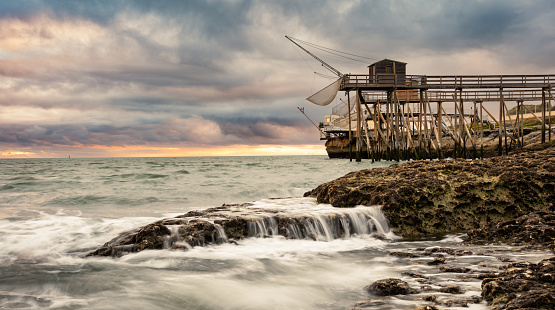 Traditional fisherman hut on stilts with carrelet fishing net. Typical wooden houses for fishing at beach
