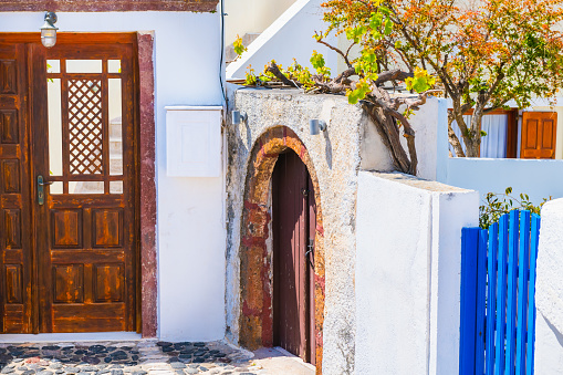White cycladic architecture in Santorini island, Greece. Wooden doors and decorative trees in the courtyard