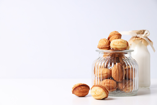 Nuts cookies in a glass jar with a bottle of milk