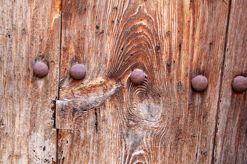 Old rusty nails driven into a wooden door seen from the front