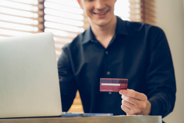 istock Young man using laptop with credit card for internet banking. Unveiling 2149096048