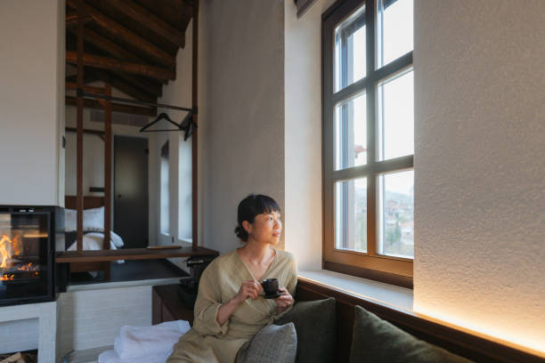 Enjoying my first cup of tea Photo of an Asian woman drinking tea in the living room and enjoying the calmness of the morning staycation hotel asian stock pictures, royalty-free photos & images