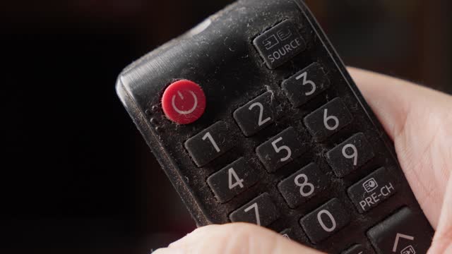 Holding Tv Remote Control and Pressing On-Off Red Button By Thumb, Close up