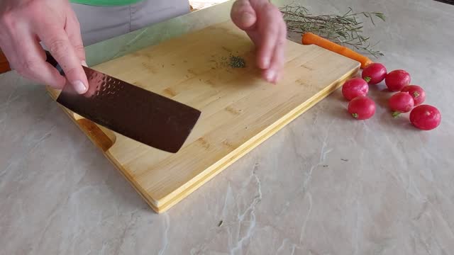 Cuting Fresh Rosemary on wooden board with Japanese ryukiri nikiri knife