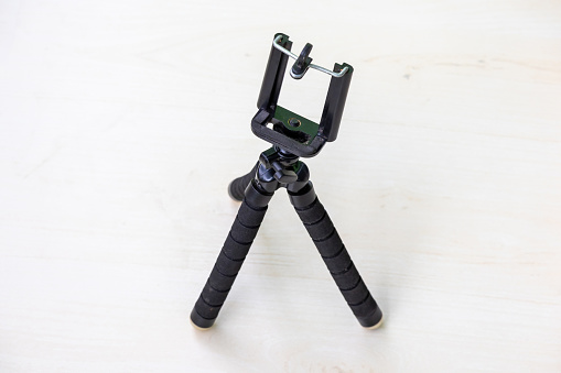 Flexible mini octopus tripod compatible with smartphones and cameras with bracket Holder Mount on a wooden textured background.