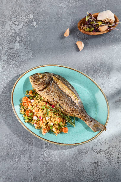 istock Grilled Dorado over Bulgur and Vegetable Medley Elegantly Presented on a Textured Plate 2149097228
