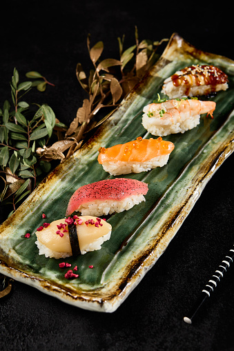 Assorted Sushi Delights with Salmon, Tuna, Shrimp, Eel, and Scallop on a Rustic Plate.