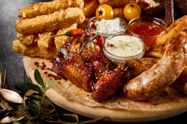 istock Friends Enjoying Assorted Beer Snacks at Evening Gathering: Toasts, Sausages, Calamari, Onion Rings, Buffalo Wings 2149097563