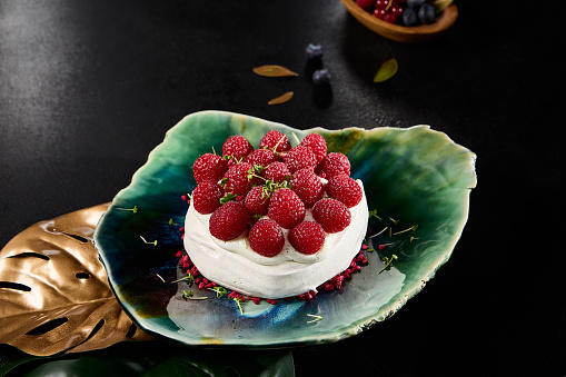 Gourmet Pavlova Dessert with Fresh Raspberries on Elegant Plate.