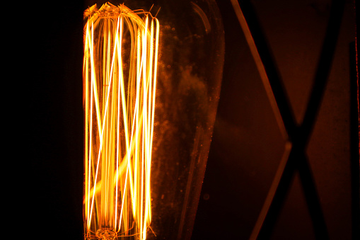 Vintage incandescent lamp. Shines yellow light. Macro photo.