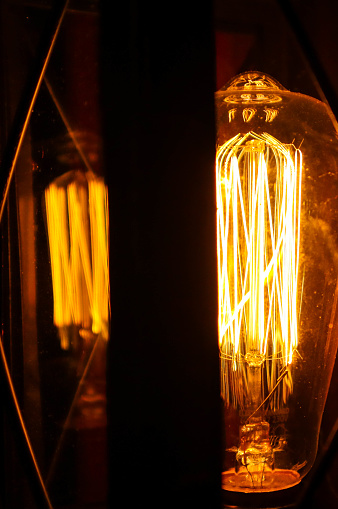 Vintage incandescent lamp. Shines yellow light. Macro photo.
