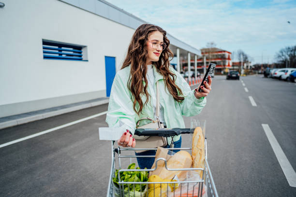 istock Woman with shopping cart using phone 2149101143