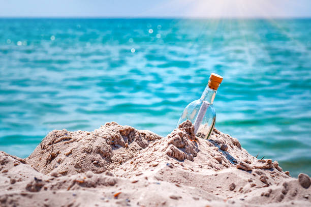 Message in a glass bottle on the beach sand under sunlight