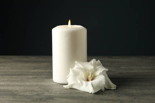istock Candle and flower on wooden table on black background 2149101792