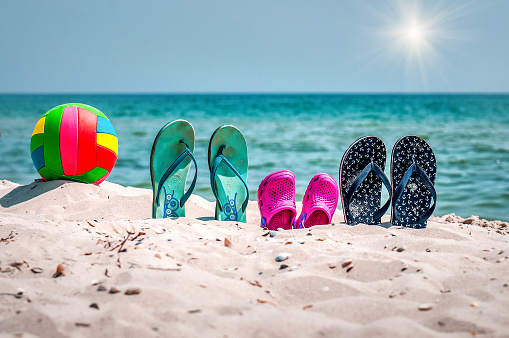 Beach summer holiday, Flip flops and ball on the sand under sunlight. Vacation theme