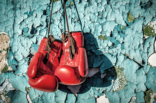 Red professional boxing gloves on the cracked paint wall