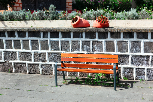 Wooden bench in front of a stone wall with flowers in pots