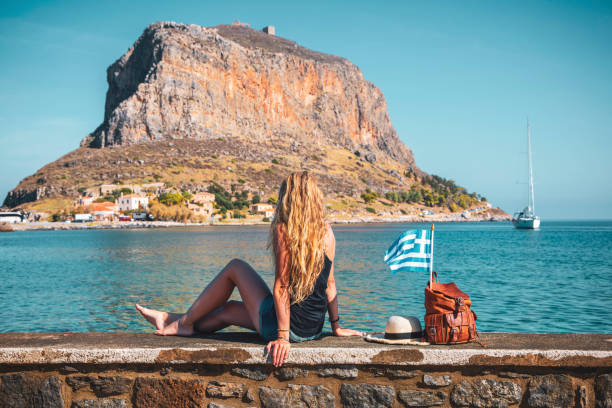Young female tourist with bag, summer hat and greek flag traveling in Greece- Travel, vacation or tour tourism concept Young female tourist with bag, summer hat and greek flag traveling in Greece- Travel, vacation or tour tourism concept monemvasia stock pictures, royalty-free photos & images