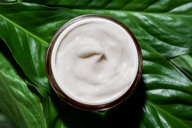 istock Natural cosmetic cream on green leaves 2149105505