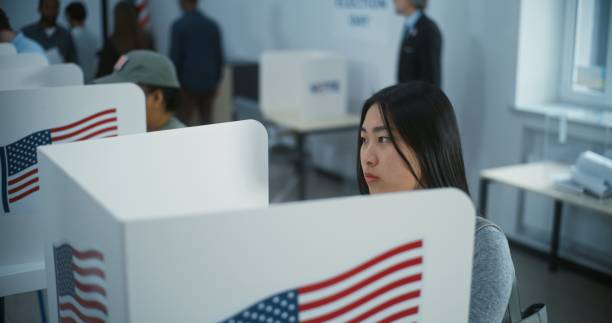istock Asian female American citizen votes in booth in polling station 2149106614