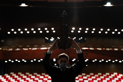 Rear view of a man playing violin in an empty theater