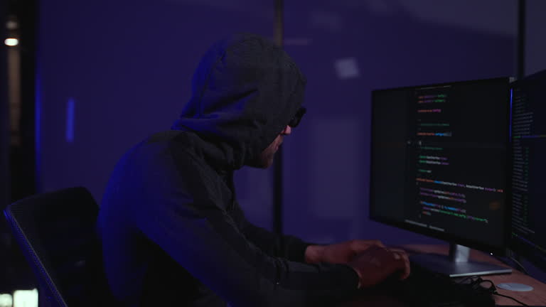 Programmer writes code for Hacker attack. Hacker holding finger on lips