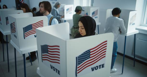 istock Arabic woman in hijab votes in booth in polling station office 2149109480