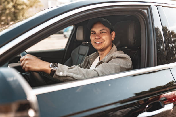 istock Young smiling man sitting in a car with open window 2149109591