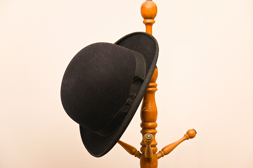 Lost Bowler hat on a wooden coat rack.