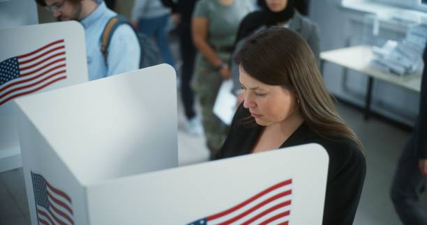 istock Female American citizen votes in booth in modern polling station 2149110294